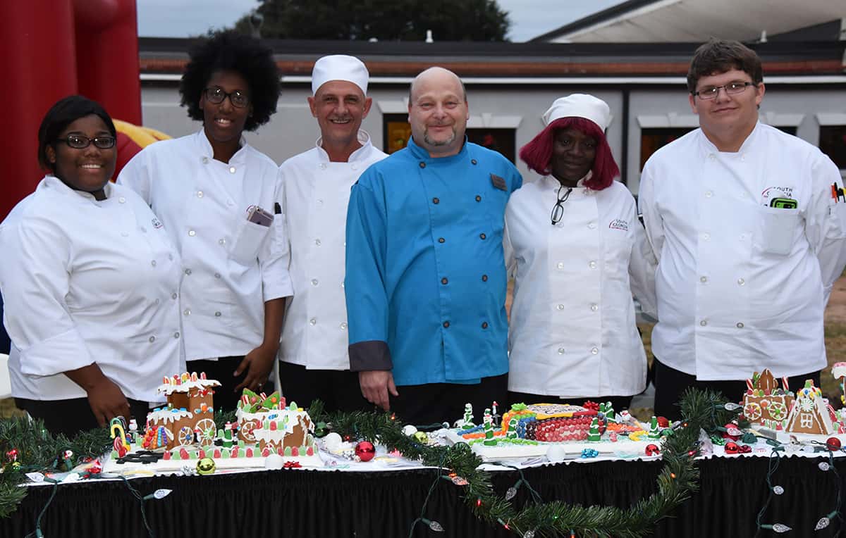 SGTC Culinary Arts Instructor Chef Ricky Watzlowick and some of his students are shown above in front of the ginger bread houses that they made for the event.