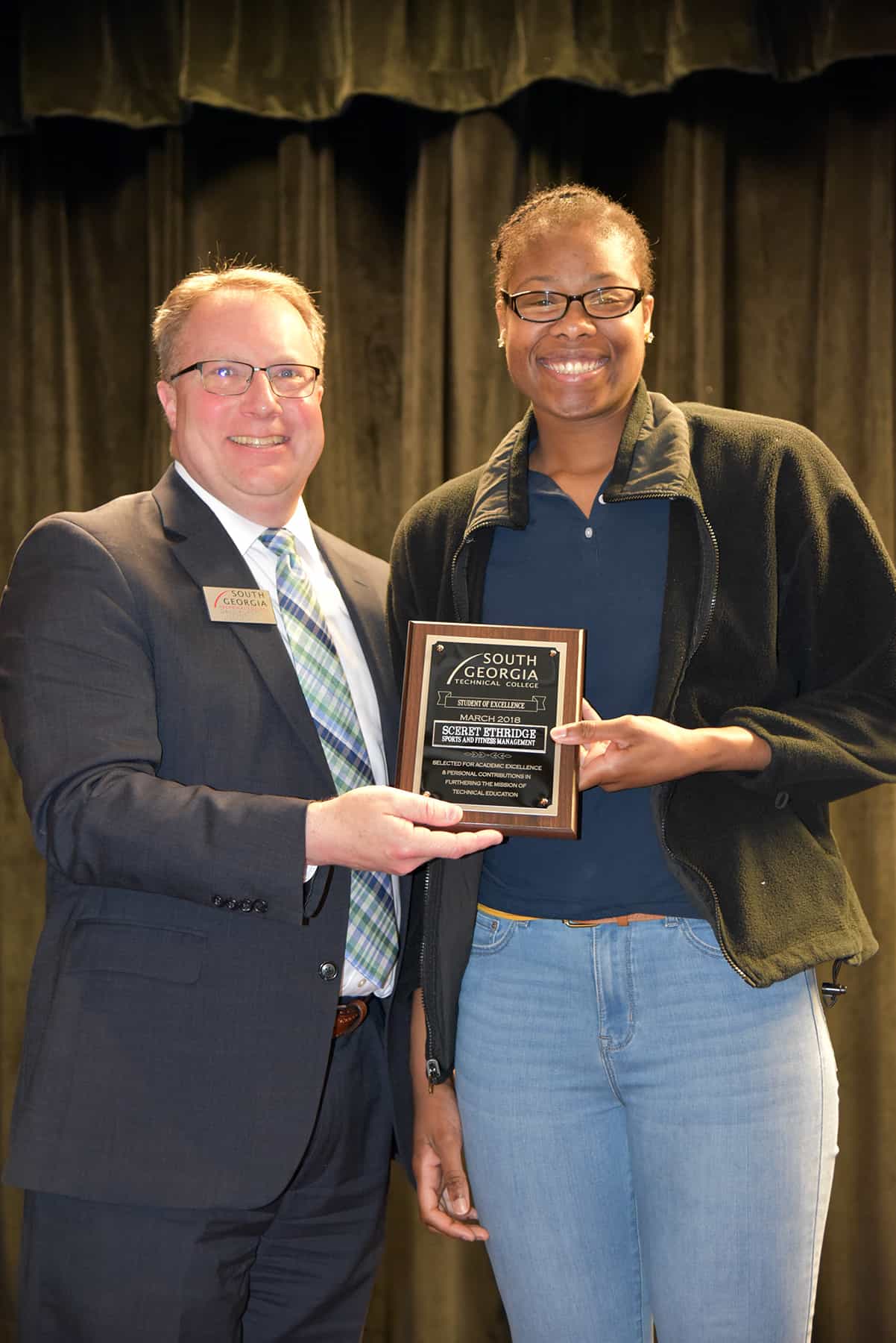 A male hands a female a plaque.