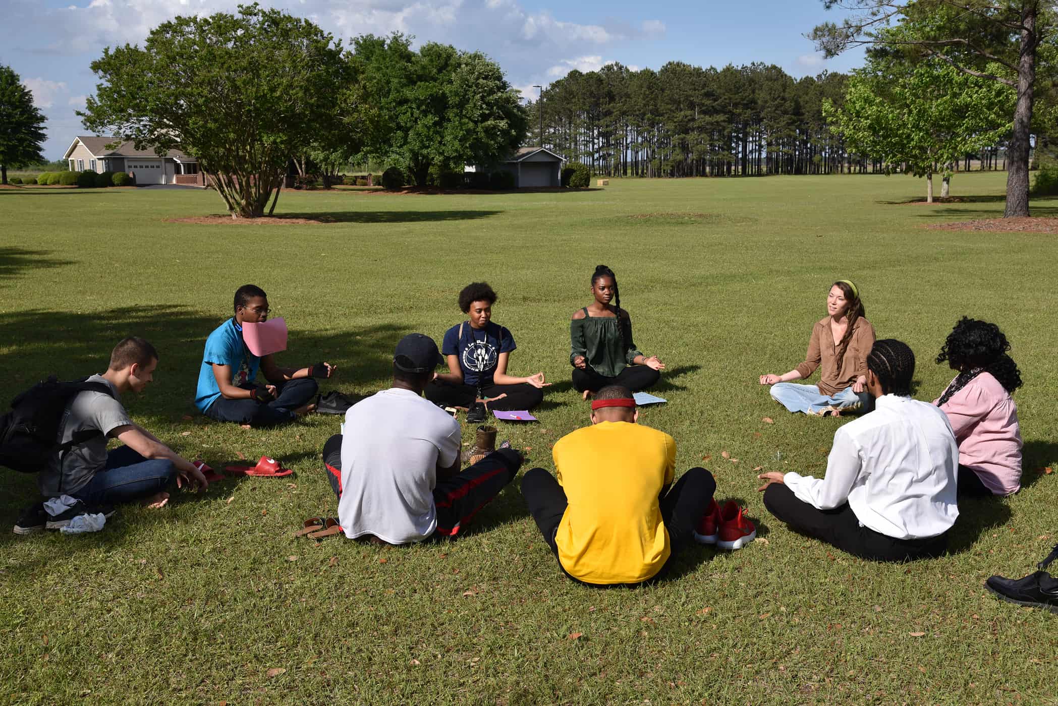 Individuals sit in a circle with their legs crossed.