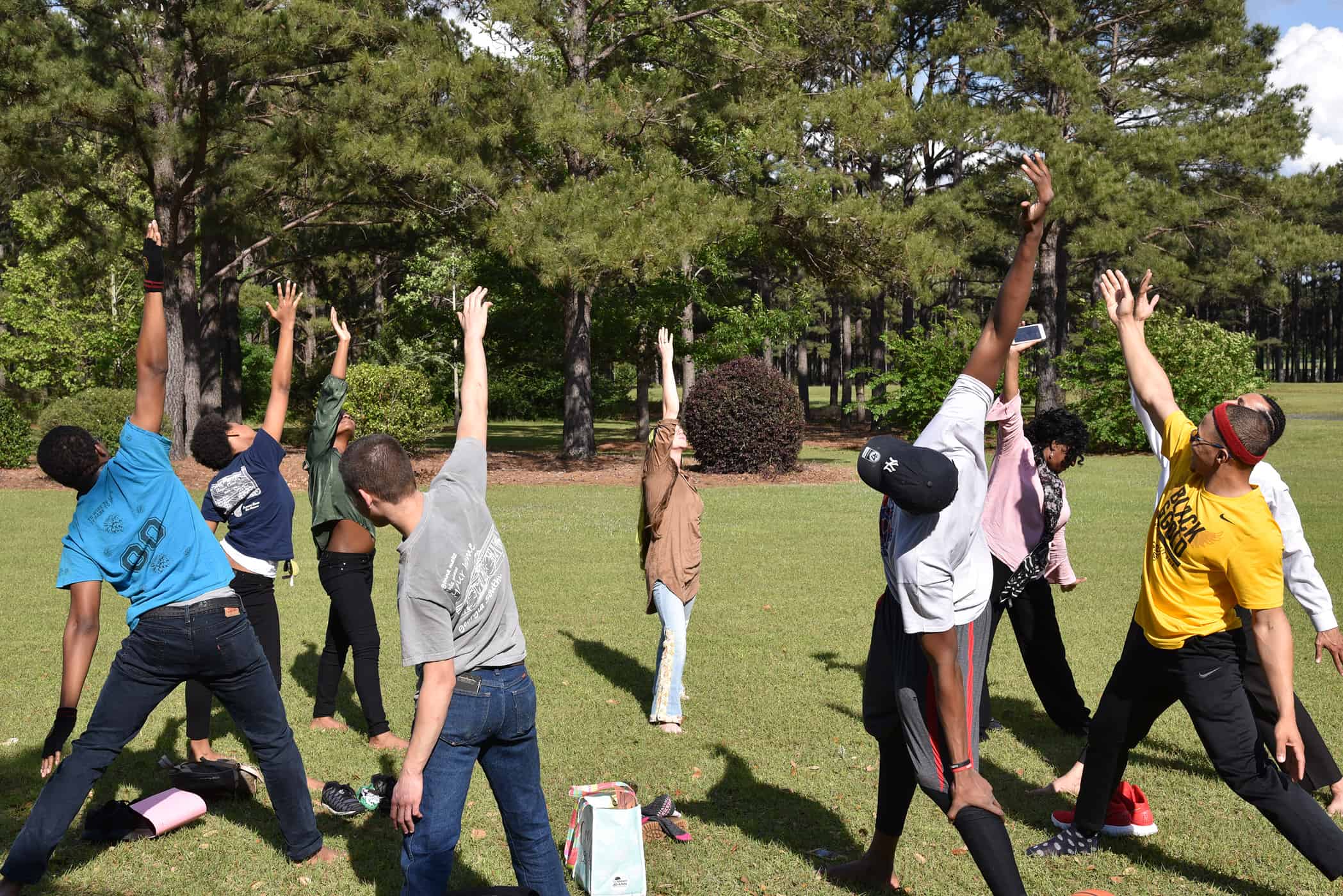 Students stand in a circle doing a yoga pose.