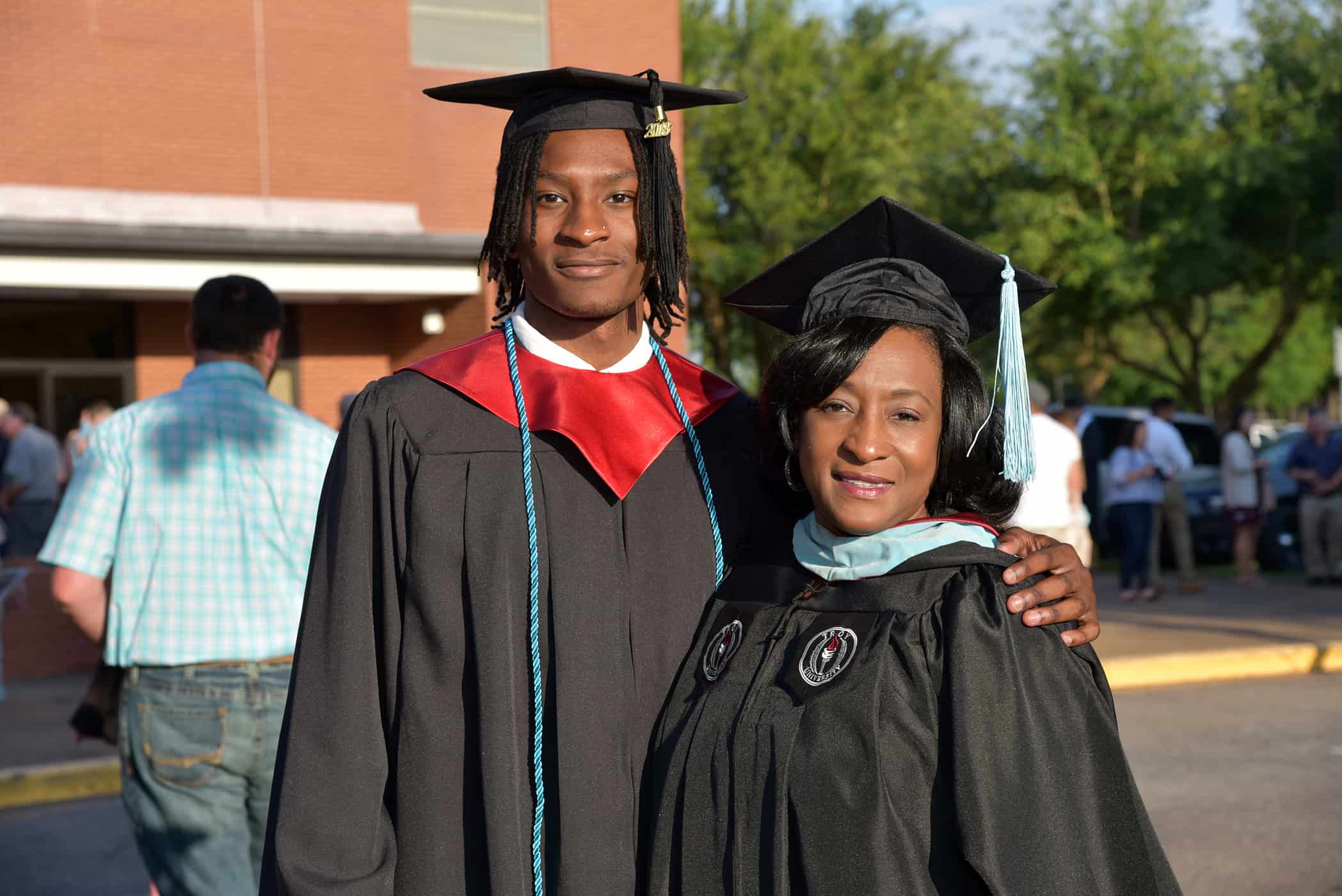 A male and female in black graduation cap and gowns stand together.