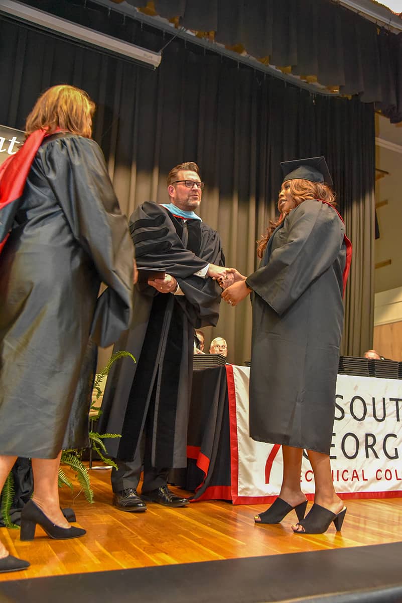 South Georgia Technical College President Dr. John Watford (center) shakes Jamera Mitchell’s hand (right) as SGTC Vice President of Student Affairs Karen Werling (left) prepares to present her work study student with her associate degree diploma.