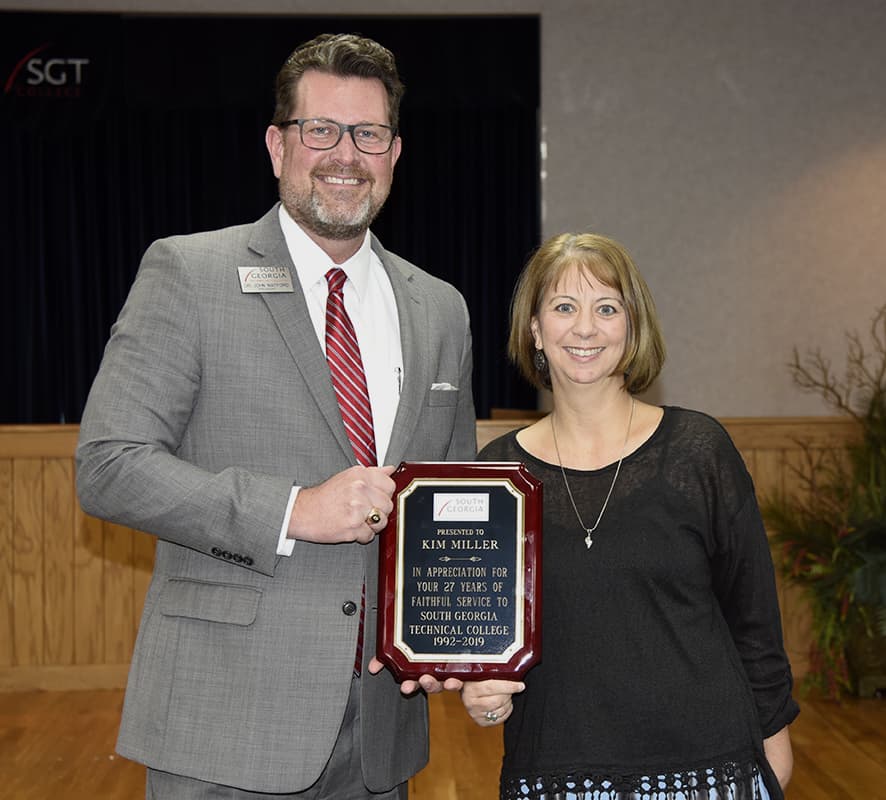 SGTC President Dr. John Watford presents Kim Miller a plaque at her retirement reception commemorating her years of service to SGTC.