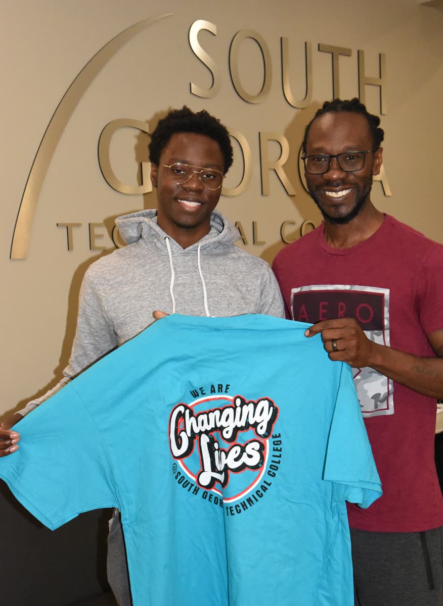 Malachi Anderson and his father, Sebastian are shown above displaying a SGTC t-shirt with the slogan “Changing Lives.” SGTC helped changed Sebastian and his father’s life and now he is entrusting the college with his son.