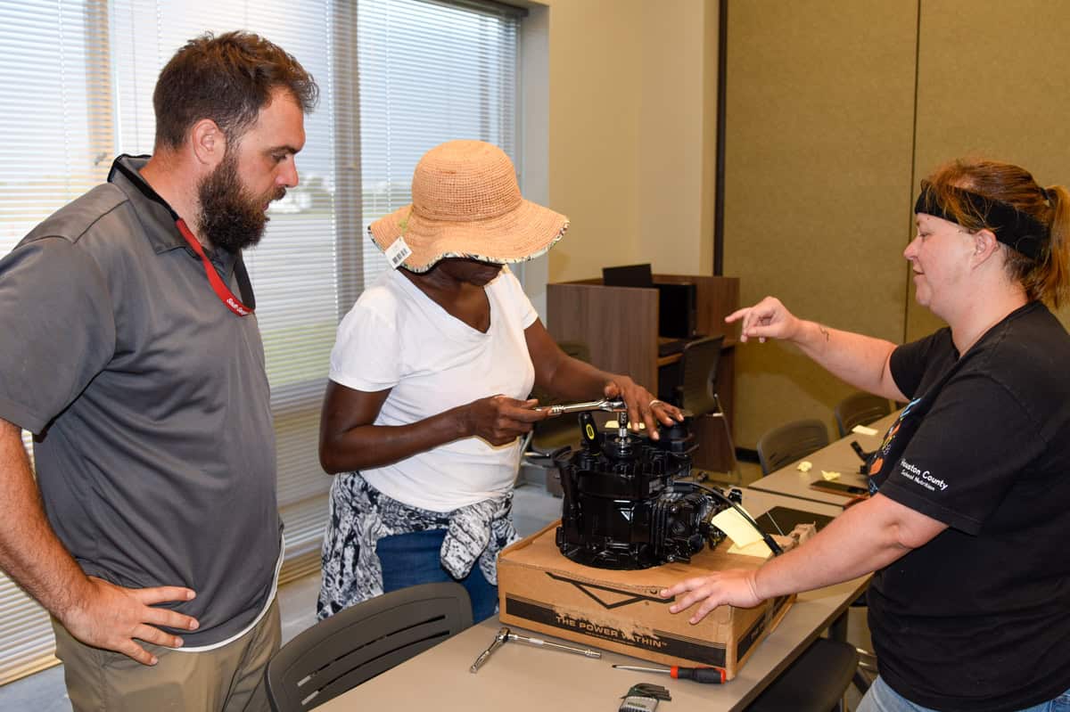 SGTC Horticulture instructor Brandon Gross (left) observes students Cassie Williams and Lisa Sellers as they disassemble a lawnmower engine.